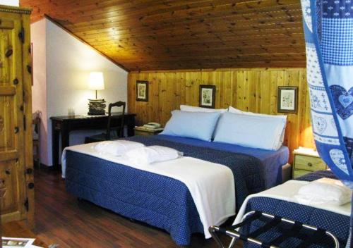 a bedroom with two beds with blue and white sheets at Hotel Bucaneve in Pré-Saint-Didier