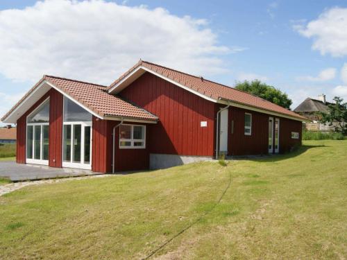 une maison rouge avec une cour herbeuse devant elle dans l'établissement 10 person holiday home in Augustenborg, à Asserballeskov