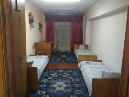 um quarto com três camas e uma secretária em Готель на Автовокзалі em Poltava