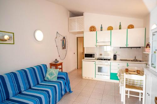 a living room with a blue couch and a kitchen at Casa Podda in San Teodoro