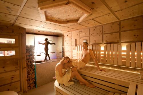 a man and a woman sitting in a sauna at Wellnessresidenz Alpenrose in Maurach