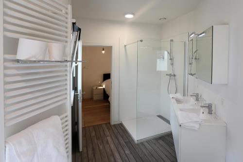 a white bathroom with a shower and a sink at Loft vakantiehuis in Veurne