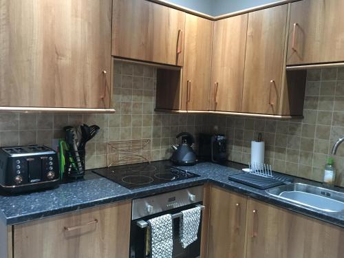 a kitchen with wooden cabinets and a stove top oven at Assembly View - two bedroomed apartment with parking permit in Ludlow Town Centre in Ludlow