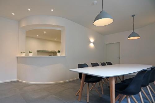 a dining room with a white table and chairs at Loft vakantiehuis in Veurne