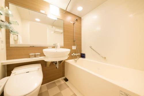 a bathroom with a toilet and a sink and a tub at Richmond Hotel Asakusa in Tokyo