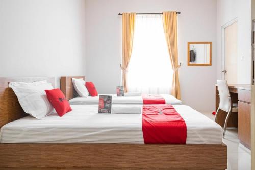 a bedroom with two beds with red and white pillows at RedDoorz near Siloam Karawaci 3 in Tangerang