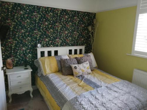 1 cama en un dormitorio con papel pintado con motivos florales en Charming pink house with perfect location, en Whitstable