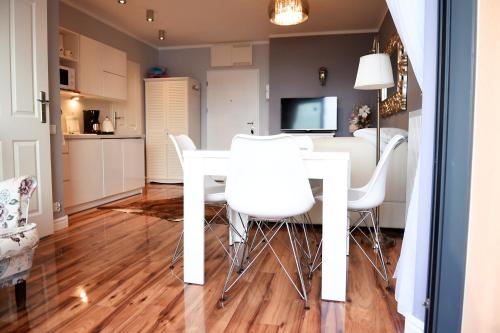 a dining room with a white table and white chairs at Apartament Lawendowa Przystań in Międzyzdroje