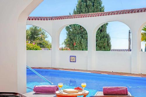 a swimming pool with two chairs and a table with drinks at Private Heated Pool, Jacuzzi & 1225m2 garden in Villa Cipreses in Frigiliana
