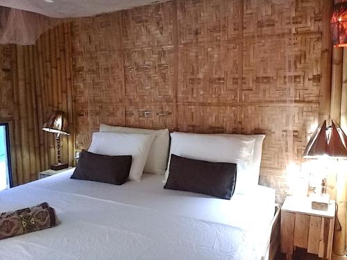
a bed with a white comforter and pillows at Herbs Guest House and Restaurant in Moalboal
