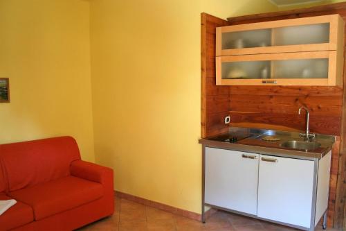 cocina con fregadero y silla roja en Agriturismo Ai Due Laghi, en Gambulaga