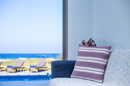 a couch with a pillow and a view of the beach at Rhodes Sea Villas in Ixia
