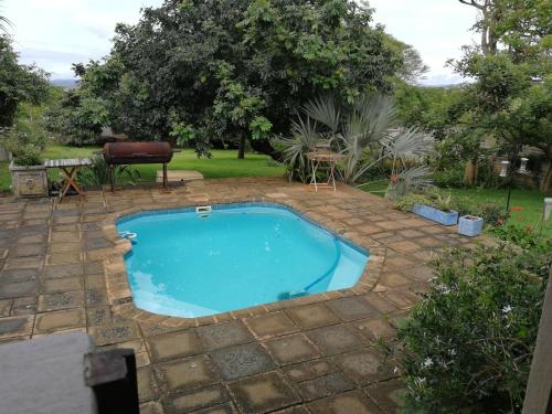 a small swimming pool in a yard with a patio at Umsinsi Cottage in Hluhluwe
