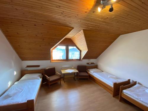 a room with two beds and a table and a window at Chata - Penzión Oravice in Zákamenné