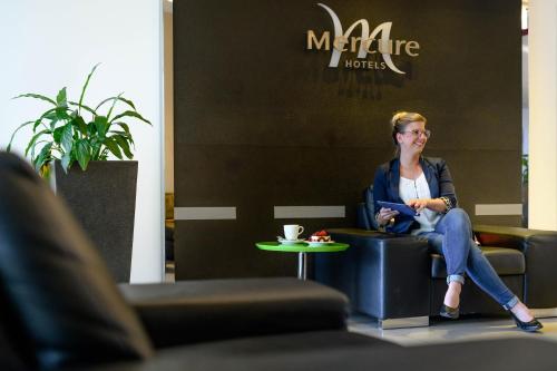 a woman sitting in a chair in a room at Mercure Hotel Köln West in Cologne