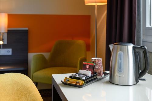 a coffee maker sitting on a table with a chair at Mercure Hotel Köln West in Cologne