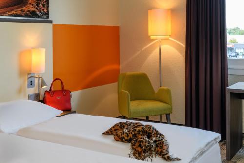 a hotel room with a bed and a chair at Mercure Hotel Köln West in Cologne