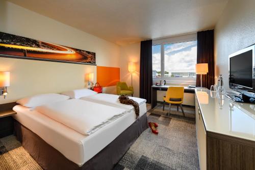 a hotel room with a large bed and a desk at Mercure Hotel Köln West in Cologne