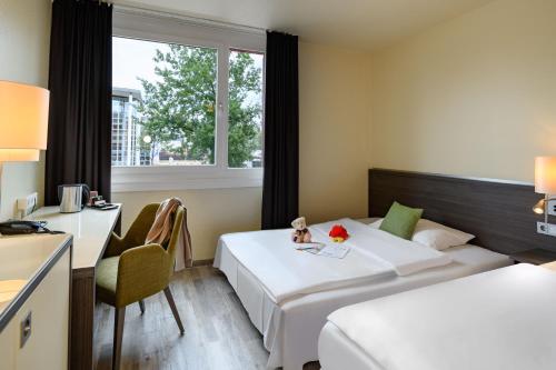 a hotel room with two beds and a desk and a window at Mercure Hotel Köln West in Cologne