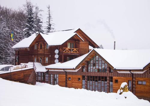 uma cabana de madeira na neve com neve em Dachna Sadyba PB em Migovo
