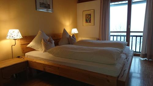 a bedroom with a bed with two lamps and a window at Landhäusl in Weissensee