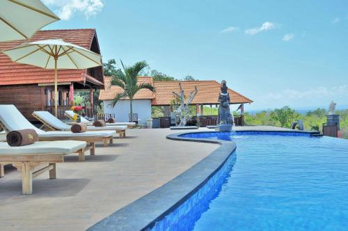 a swimming pool with lounge chairs and an umbrella at Reynten Hill Resort in Nusa Penida