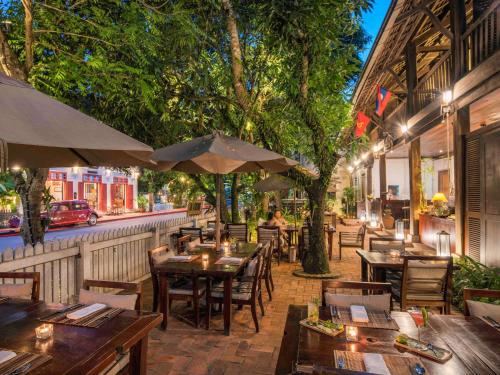 a restaurant with tables and umbrellas on a patio at 3 Nagas Hotel Luang Prabang - MGallery Collection in Luang Prabang