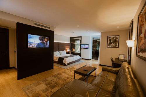 a living room with a couch and a bed and a television at Privilege Hotel & Spa in Tirana