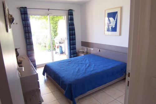 サリ・ソランザラにあるPALMERAIE 220のベッドルーム1室(青いベッド1台、ガラスのスライドドア付)