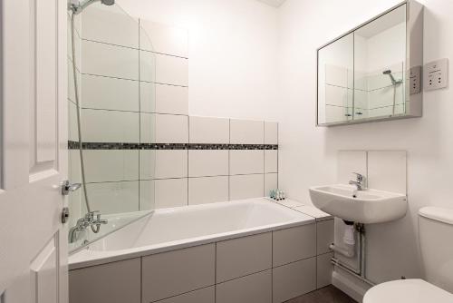 a white bathroom with a tub and a sink at Riverside Luxury Apartment in Rochester