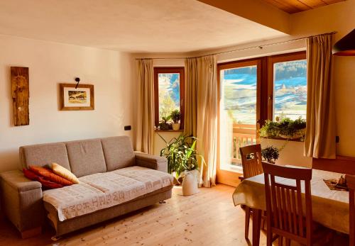 a living room with a couch and a table and windows at Apartment HaNiLe in Sarntal