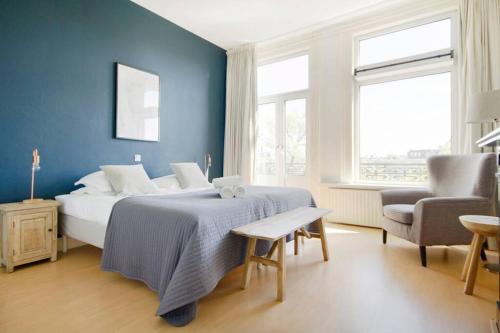 a blue bedroom with a bed and a chair at 2 Bedroom 2 Bathroom Canal Apartment in Amsterdam