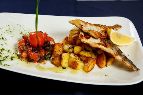 a white plate of food with fish and potatoes at Terra Hotel in Bansko