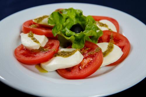 a white plate with tomatoes and cheese and lettuce at Terra Hotel in Bansko