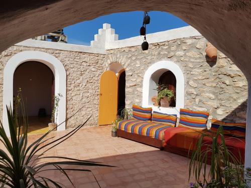 d'une terrasse avec un canapé sur un mur en pierre. dans l'établissement Ranch de Sidi kaouki, à Essaouira