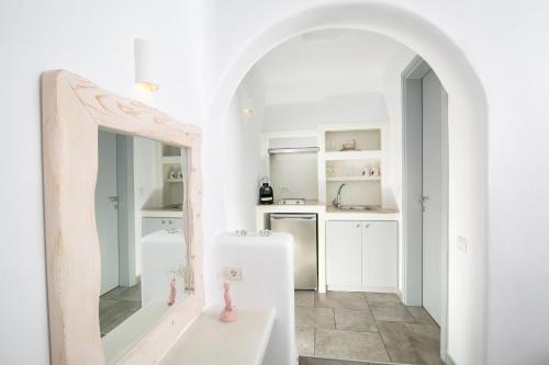 a white kitchen with a mirror and a sink at Anemoessa Villa in Oia