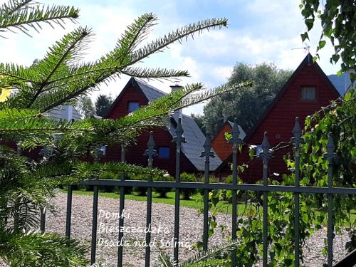 a fence in front of a house with trees at Domki nad Soliną - Bieszczadzka Osada 512-823-385 in Solina