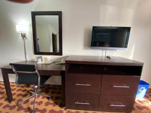a desk with a mirror and a television in a room at Lodge Inn Wrightstown - Fort Dix in Wrightstown