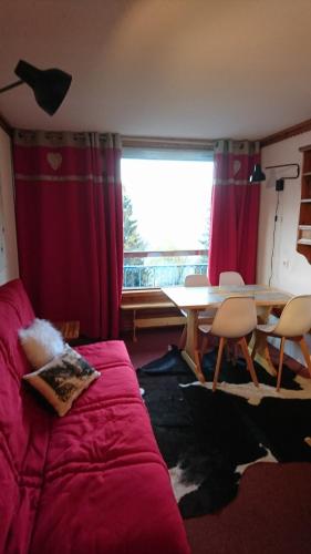 un salon avec une table et un canapé rouge dans l'établissement Bourg St Maurice les Arcs 1800 Les Lauzieres jolie vue, nature, espace, bien être, plaisir, paisible, à Arc 1800