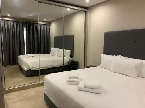 ein Schlafzimmer mit einem großen weißen Bett und einem Spiegel in der Unterkunft 77 On Burger in Polokwane