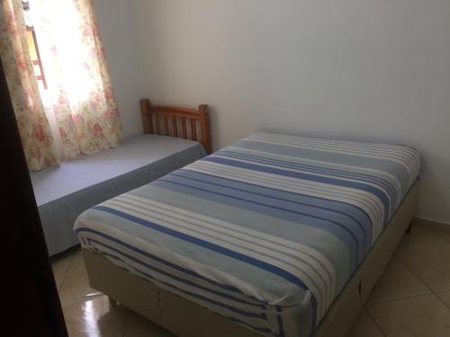 a small bedroom with a bed and a window at Apartamento em Bertioga sp in Bertioga