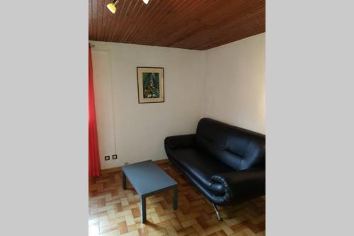 a living room with a black leather couch and a table at ST LARY-VIGNEC Charmant studio au calme in Vignec