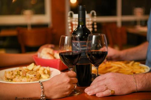 two people holding wine glasses at a table with a plate of food at Bernie's Bed & Breakfast , A 3 KILOMETROS DEL AEROP EZEIZA, VAN ,IN-OUT, FREE EZEIZA AIRPORT in Ezeiza