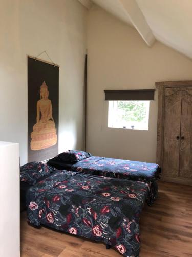 een slaapkamer met 2 bedden en een schilderij aan de muur bij Les Gîtes Ecosphère in Genappe