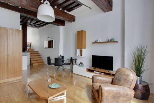 a living room with a couch and a tv and a table at Luminous Loft in Saint-Germain des Prés in Paris