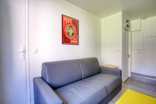 a blue couch in a room with a picture on the wall at Magnificent Studio Near The Canal De L'ourcq in Paris