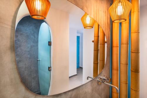 a round mirror in a bathroom with a blue surfboard at Evgenia Villas & Suites by Calm Collection in Fira