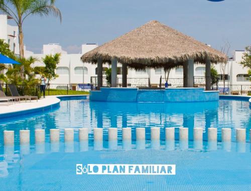 a swimming pool at a resort with a straw hut at Bonita Casa en Condominio con Alberca y Acceso al Lago in Tequesquitengo
