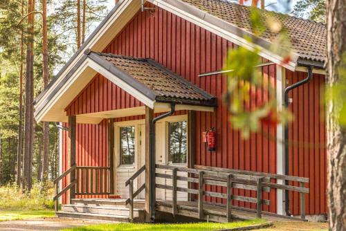 a small red building with a porch in the woods at First Camp Duse Udde - Säffle in Säffle