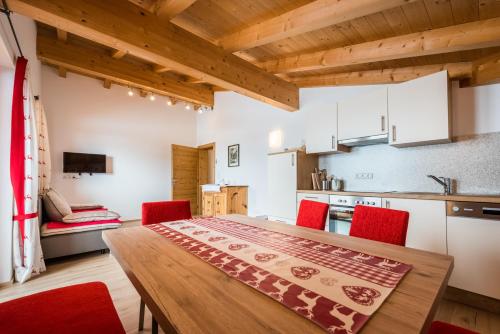 cocina y comedor con mesa de madera y sillas rojas en Nockhof, en Terfens
